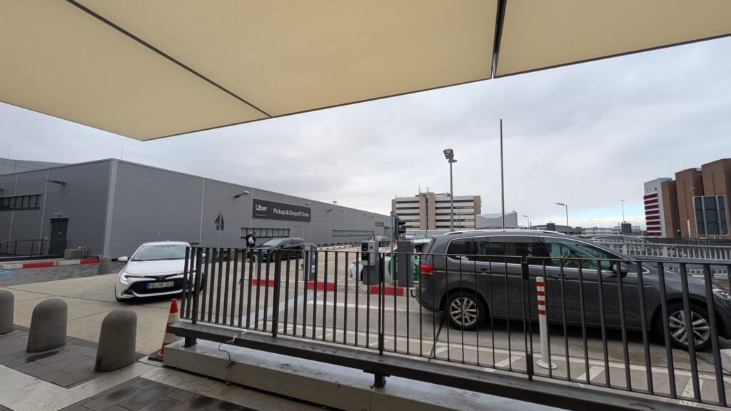 Uber pickup zone building at Frankfurt Airport — black Uber cars waiting outside Terminal 1 in March 2026 